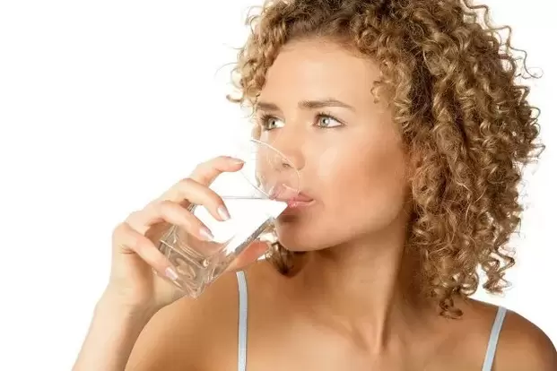 A rapaza segue unha dieta para os preguiceiros, bebendo un vaso de auga antes de comer